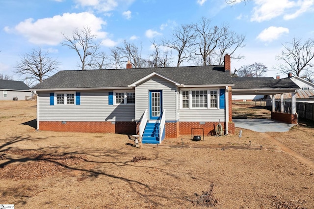 view of front of home with driveway, a chimney, an attached carport, and entry steps