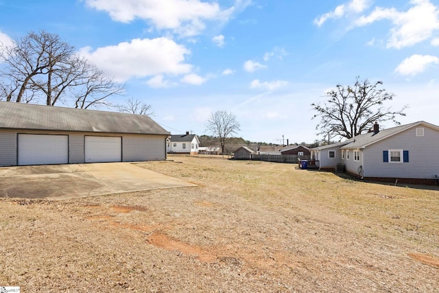 view of yard featuring a garage, an outbuilding, and fence