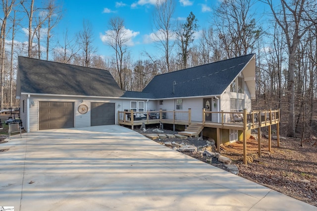 view of front of property with an attached garage, driveway, a deck, and roof with shingles