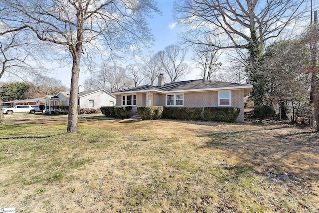 ranch-style house featuring a chimney, a front lawn, and brick siding