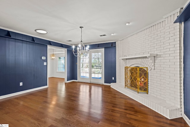 unfurnished living room featuring a brick fireplace, visible vents, wood finished floors, and ornamental molding