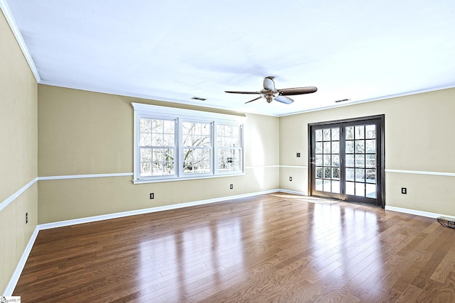 spare room with ornamental molding, visible vents, and wood finished floors