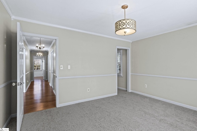 carpeted empty room with crown molding, baseboards, and an inviting chandelier