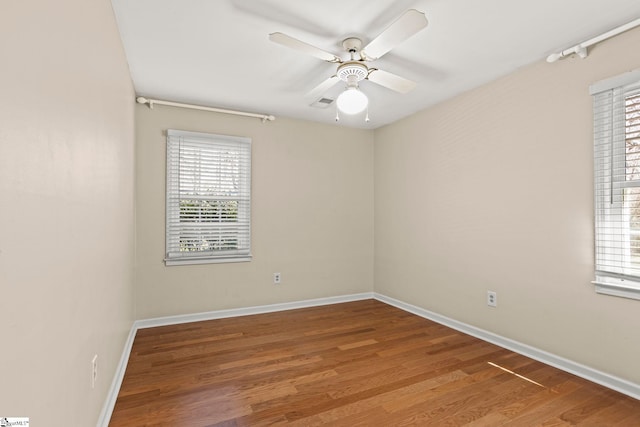 spare room featuring ceiling fan, baseboards, and wood finished floors