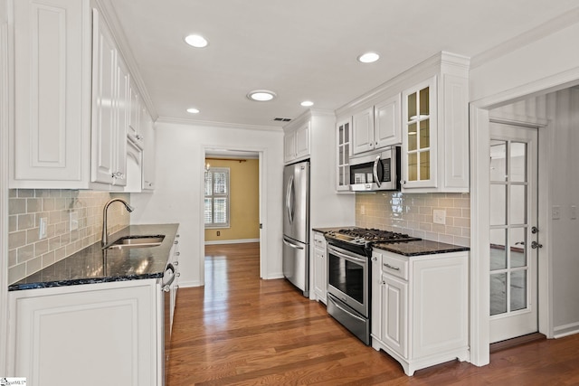 kitchen with white cabinetry, stainless steel appliances, a sink, and wood finished floors