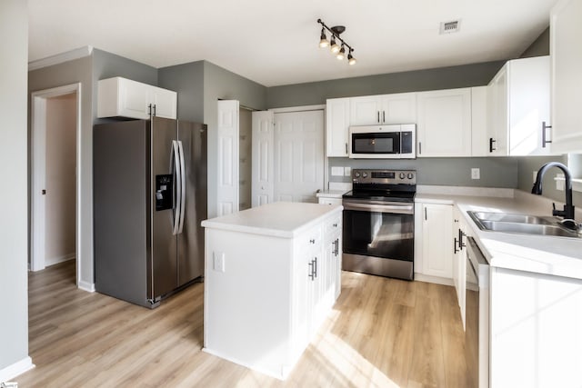 kitchen featuring visible vents, light wood-style flooring, appliances with stainless steel finishes, light countertops, and a sink