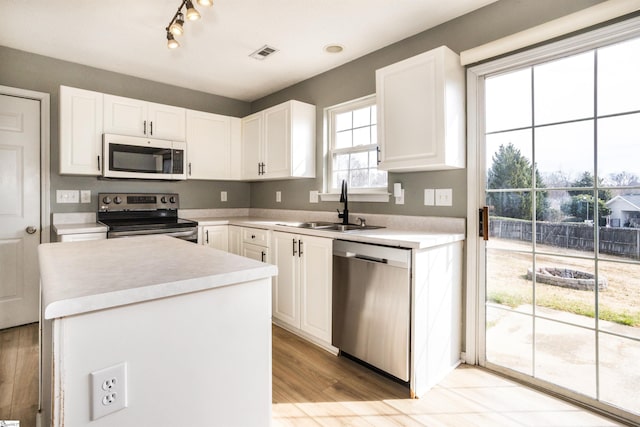 kitchen with a sink, visible vents, white cabinetry, light countertops, and appliances with stainless steel finishes