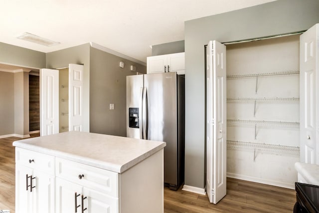 kitchen with a center island, light countertops, white cabinets, wood finished floors, and stainless steel fridge with ice dispenser