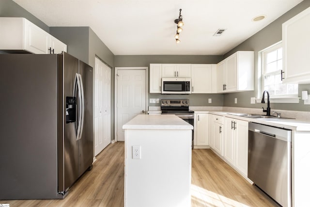 kitchen featuring stainless steel appliances, light countertops, light wood-style floors, white cabinets, and a kitchen island