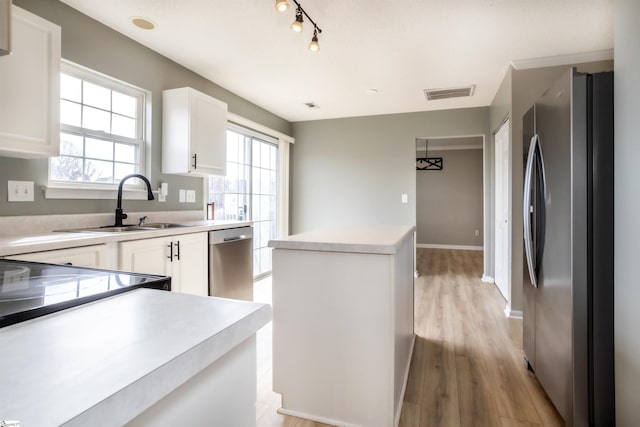 kitchen featuring visible vents, light wood-style flooring, appliances with stainless steel finishes, a center island, and white cabinetry