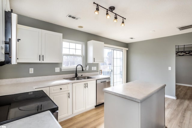 kitchen featuring visible vents, light wood-style flooring, stainless steel dishwasher, a kitchen island, and a sink