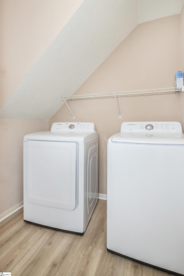 washroom featuring laundry area, baseboards, washer and clothes dryer, and wood finished floors