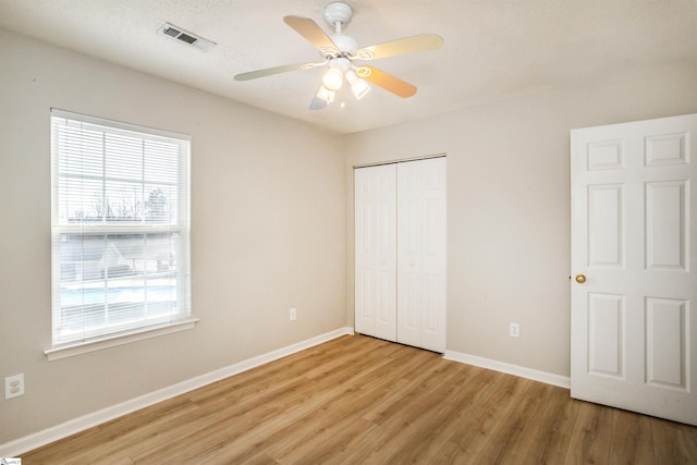 unfurnished bedroom featuring a ceiling fan, visible vents, baseboards, a closet, and light wood finished floors