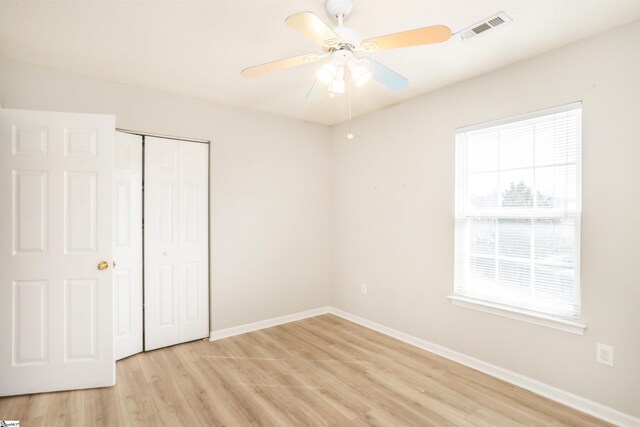 unfurnished bedroom with a closet, visible vents, light wood-style flooring, and multiple windows