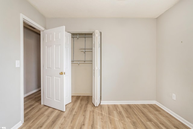 unfurnished bedroom with baseboards, a closet, and light wood-style floors