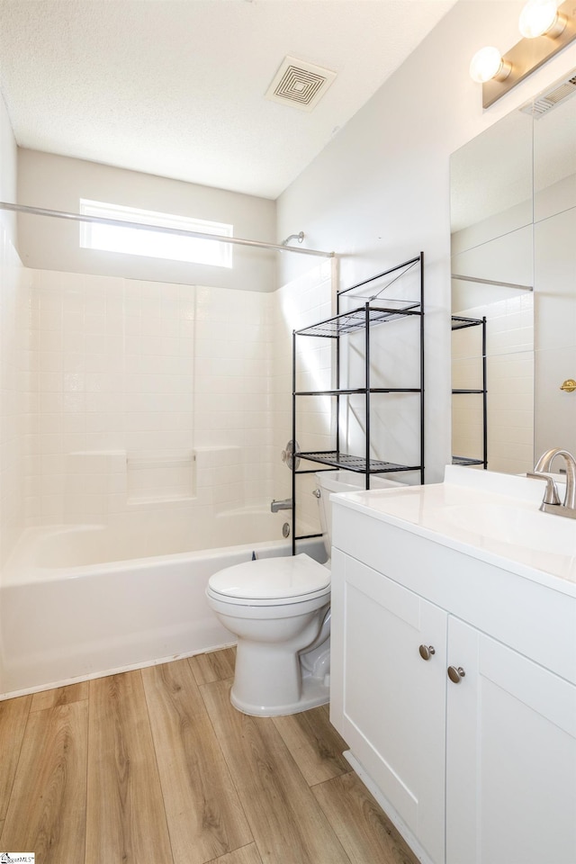 full bathroom with visible vents, toilet, wood finished floors, vanity, and shower / washtub combination