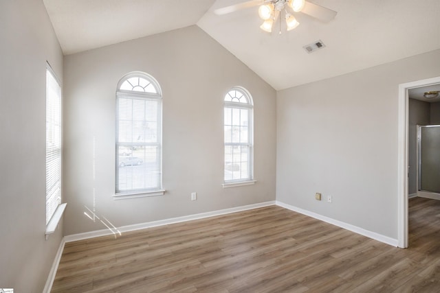 empty room featuring vaulted ceiling, baseboards, and wood finished floors