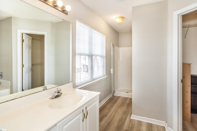 bathroom with a stall shower, baseboards, wood finished floors, and vanity