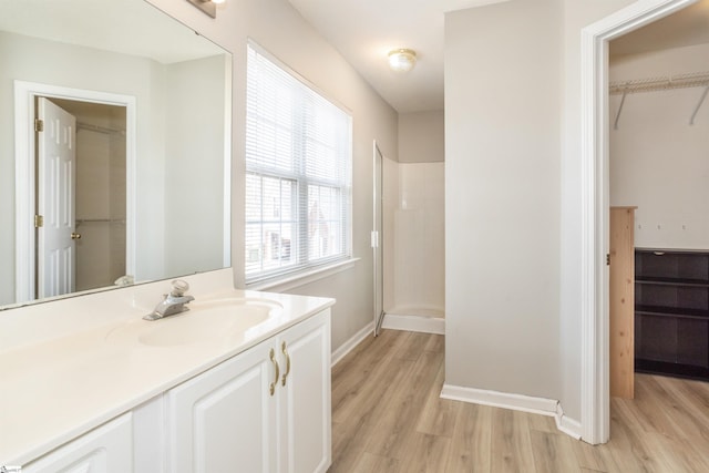 full bath with baseboards, a shower stall, vanity, and wood finished floors