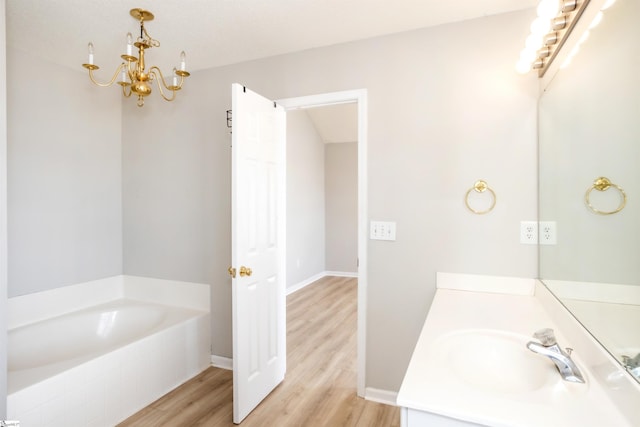 bathroom with a chandelier, wood finished floors, vanity, baseboards, and a bath