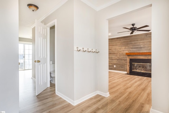 hall featuring ornamental molding, wood walls, wood finished floors, and baseboards