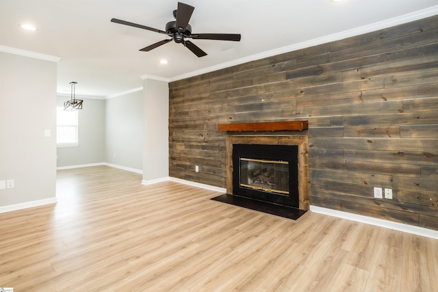 unfurnished living room with a fireplace with flush hearth, crown molding, wood walls, and wood finished floors