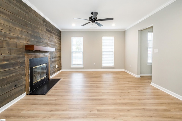 unfurnished living room featuring a large fireplace, ornamental molding, and a wealth of natural light