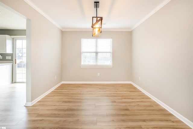 empty room with light wood-type flooring, a wealth of natural light, and ornamental molding