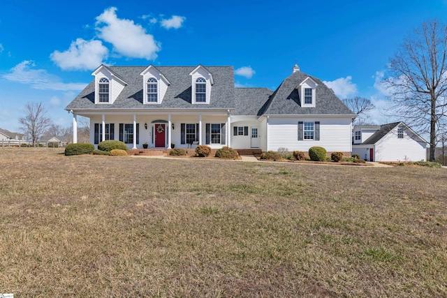 cape cod home with covered porch, a shingled roof, and a front lawn