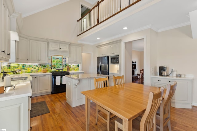 dining area with light wood-type flooring, crown molding, a high ceiling, and recessed lighting