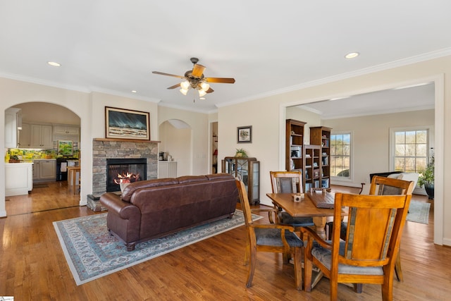 dining room featuring recessed lighting, ornamental molding, wood finished floors, and a stone fireplace