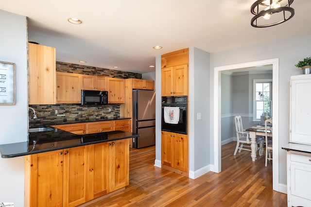 kitchen featuring black appliances, dark countertops, a sink, and decorative backsplash