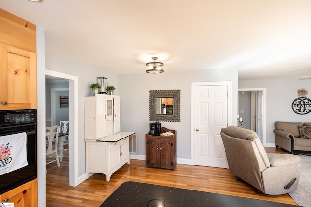 living room featuring visible vents, light wood-style flooring, and baseboards