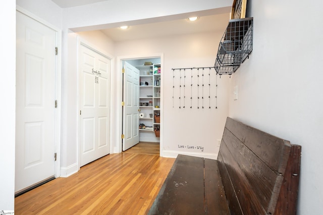 corridor with light wood finished floors, baseboards, and recessed lighting