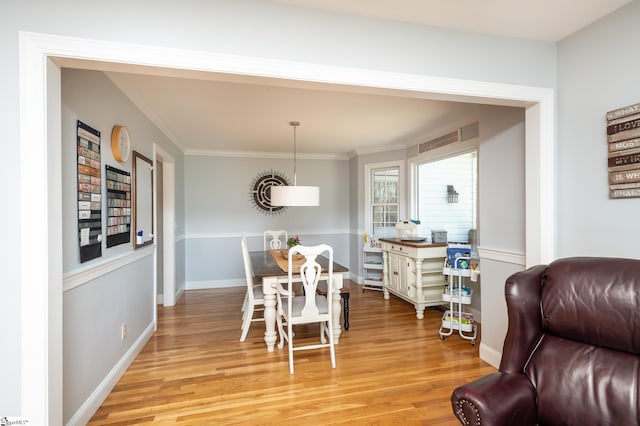 dining space featuring light wood-style floors, crown molding, and baseboards