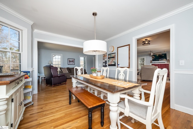 dining space featuring ornamental molding and light wood-style flooring