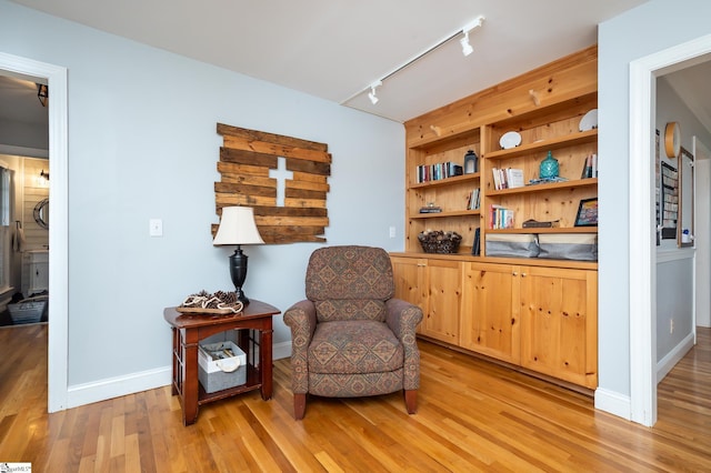 sitting room featuring light wood finished floors, rail lighting, and baseboards