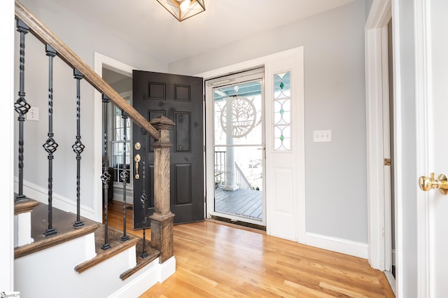 entrance foyer with light wood-type flooring, stairs, and baseboards