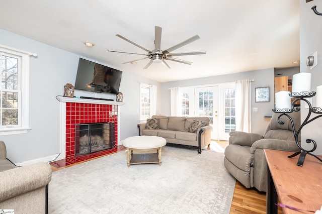 living room featuring a fireplace, wood finished floors, a ceiling fan, and baseboards