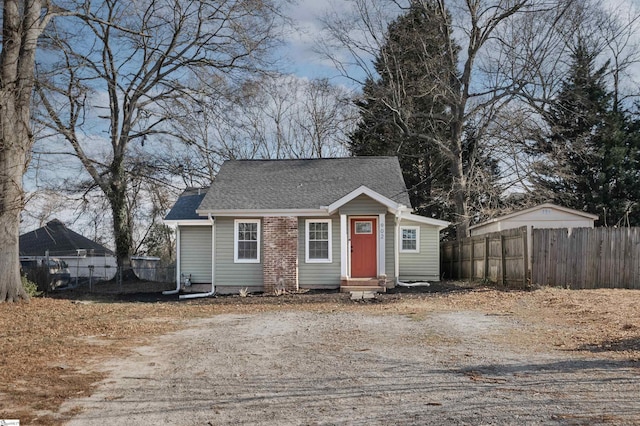 view of front of home with a shingled roof, entry steps, fence, and driveway