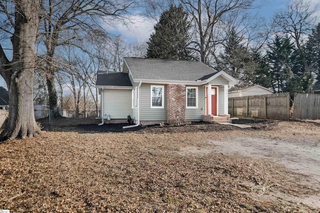 view of front of home featuring entry steps, fence, and roof with shingles