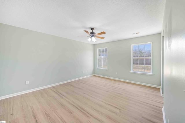 spare room with light wood finished floors, baseboards, and a textured ceiling