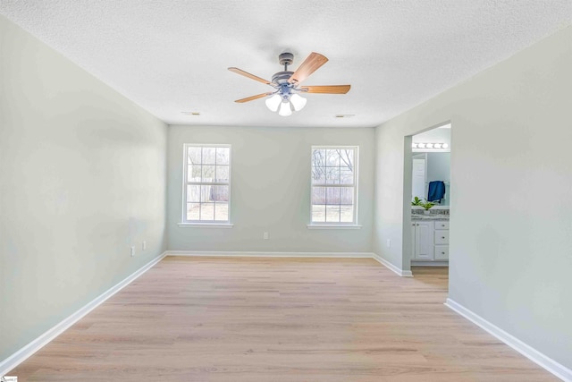 spare room with visible vents, baseboards, light wood-style flooring, ceiling fan, and a textured ceiling