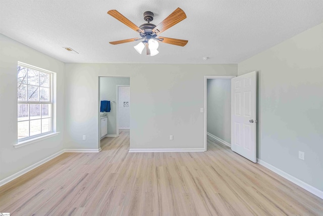 unfurnished bedroom featuring a textured ceiling, light wood finished floors, and baseboards