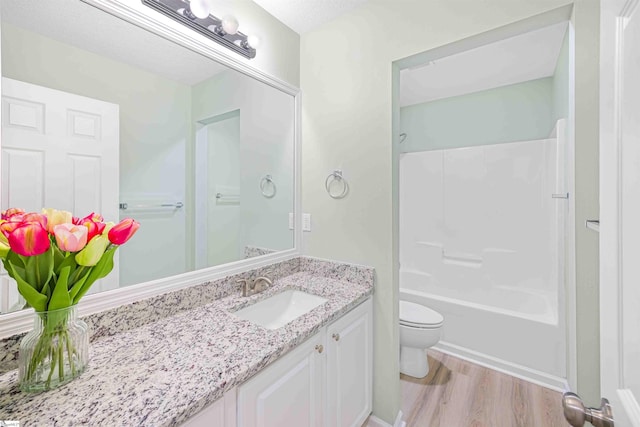 full bathroom featuring toilet, washtub / shower combination, wood finished floors, and vanity