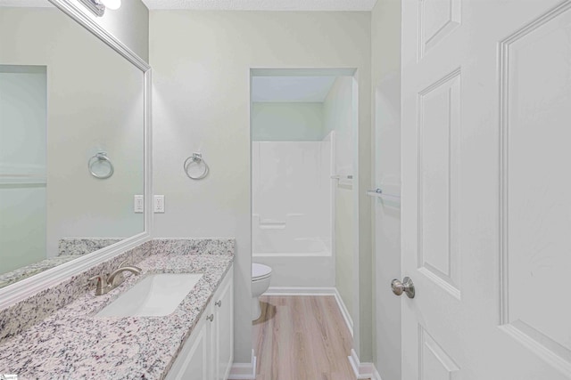 bathroom with toilet, tub / shower combination, vanity, wood finished floors, and baseboards