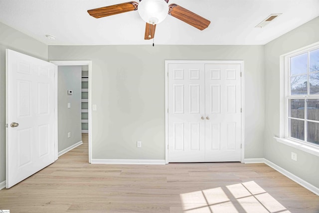 unfurnished bedroom featuring a closet, visible vents, light wood-style flooring, a ceiling fan, and baseboards