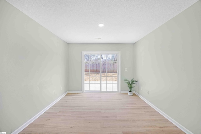 unfurnished room with a textured ceiling, light wood-style flooring, and baseboards