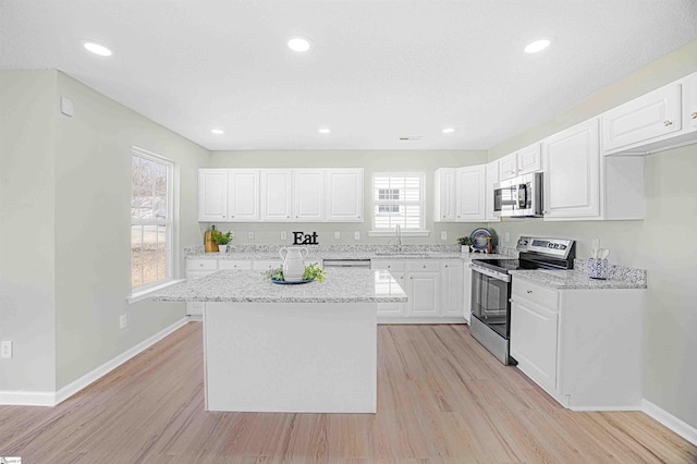 kitchen featuring stainless steel appliances, a sink, white cabinetry, and light wood-style floors