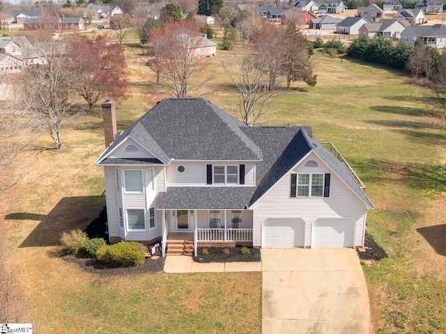 view of front facade with a chimney, a porch, an attached garage, a front yard, and driveway